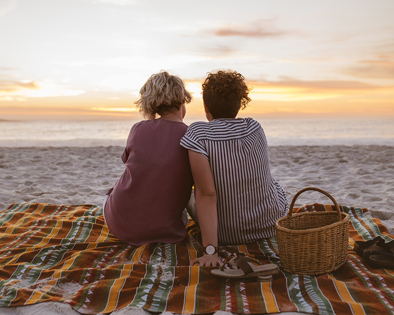 Lesbian couple outside at sunset on the beach. Couples therapy in New York with Maria Graceffa.